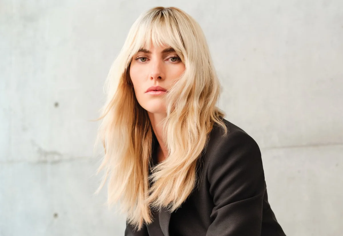 A blonde woman modelling in front of a concrete wall